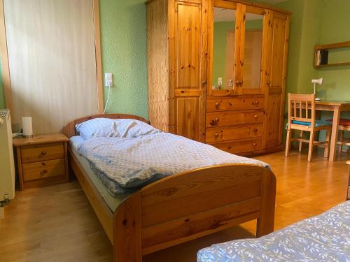 sypialnia z drewnianym łóżkiem i komodą w obiekcie Ferienzimmer Oelhaf Zimmer in Grün Self Check-In mit Key-Tresore w mieście Wilhelmsdorf