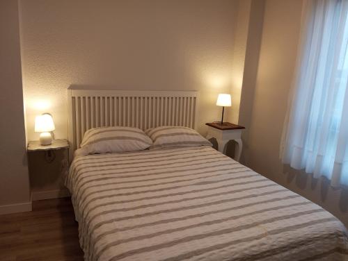 a bedroom with a large bed with two lamps at apartamento Somo in Somo