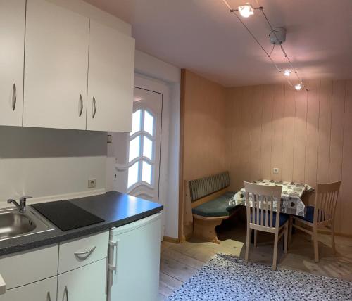 uma cozinha com um lavatório e uma mesa com uma cadeira em Alpen Ferienwohnung II em Lappago