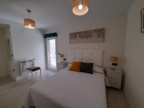 um quarto branco com uma cama grande e uma janela em Apartamento con terraza a 2,5km de las playas em Posada de Llanes