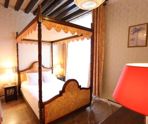 a bedroom with a four poster bed and a red lamp at Hotel de la Bretonnerie in Paris