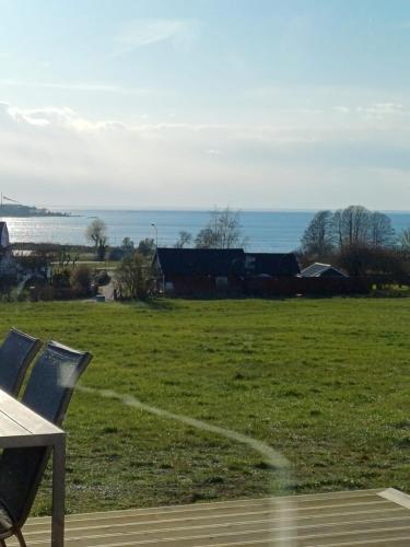 a bench in a field with the ocean in the background at Klinta sea view 2 in Köpingsvik