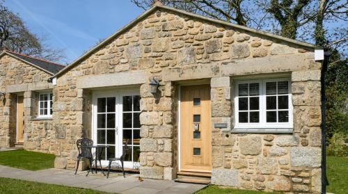 ein Steingebäude mit einer Tür und einem Fenster in der Unterkunft Sancreed House Cottages in Penzance