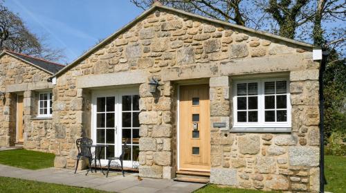 ein Steingebäude mit einer Tür und einem Fenster in der Unterkunft Sancreed House Cottages in Penzance