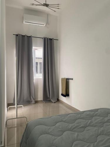 a bedroom with a bed and a window with curtains at Homestay Taman Melati Jerantut in Jerantut