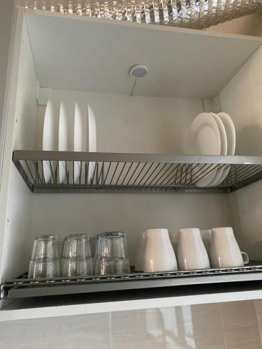 a shelf in a kitchen with dishes and plates at Homestay Taman Melati Jerantut in Jerantut
