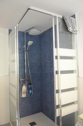 y baño con ducha de azulejos azules. en La Casina de Luarca, en Luarca