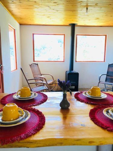 a wooden table with yellow cups and plates on top at Chales Boa Vista in Monte Verde