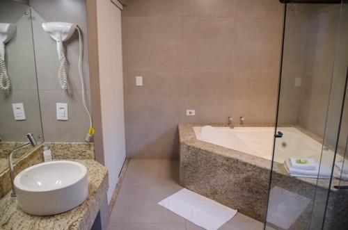 a bathroom with a tub and a sink and a shower at Ville Park Hotel in Ourinhos