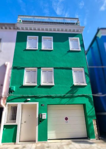 a green building with three windows and a garage at Parsifal House in Chioggia