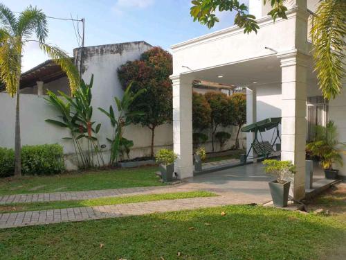 a white building with trees and plants in a yard at Vidushi Home in Minuwangoda