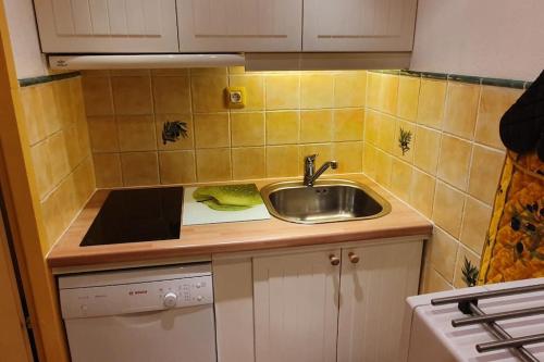 une petite cuisine avec un évier et une cuisinière dans l'établissement Appartement residence Chanteneige Les Menuires centre croisette au pieds des pistes, aux Menuires