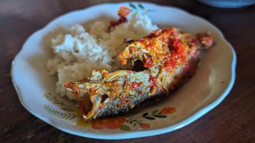 un plato de comida con un trozo de pescado y puré de patatas en Taman Baloho Indah - Hotel & Resort en Telukdalem