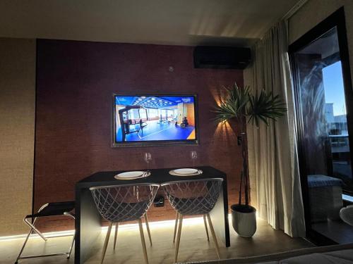 a table with two chairs and a tv on a wall at View467LifeResortBR in Brasilia