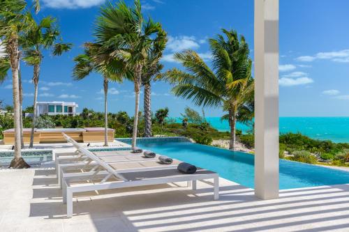 a pool with two lounge chairs and palm trees at Kailoa Villa in Long Bay Hills