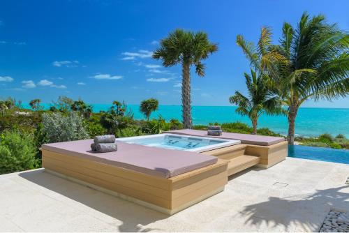 a hot tub in a patio with the ocean in the background at Kailoa Villa in Long Bay Hills