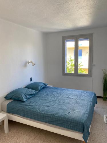 une chambre avec un lit avec une couette bleue et une fenêtre dans l'établissement Carnon Plage, 1ère ligne, balcon sur la mer, à Carnon-Plage