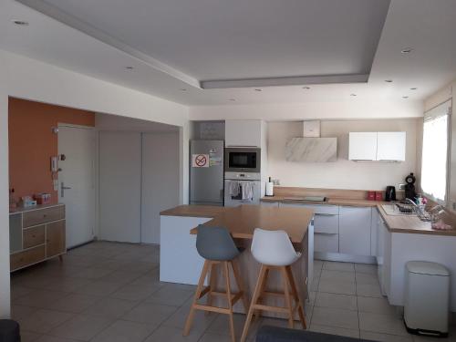 una cocina con barra y dos taburetes. en Appartement 1er étage, 66 m² en La Seyne-sur-Mer