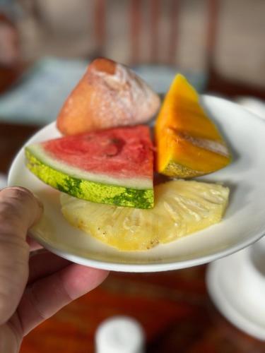 a person holding a plate of fruit on a plate at Kiwengwa Bungalow Boutique Resort in Kiwengwa