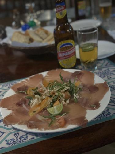 a plate of food on a table with a bottle of beer at Kiwengwa Bungalow Boutique Resort in Kiwengwa
