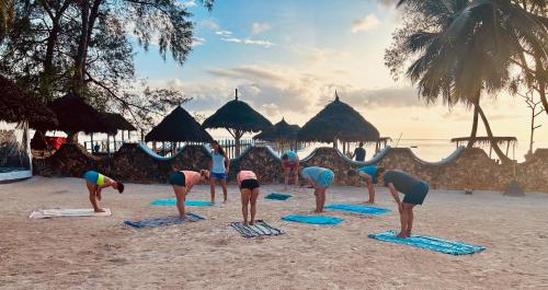 a group of people doing yoga on the beach at Kiwengwa Bungalow Boutique Resort in Kiwengwa