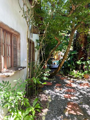 a garden with a tree next to a building at Casa da Glória Trancoso - Pousada Boutique in Trancoso