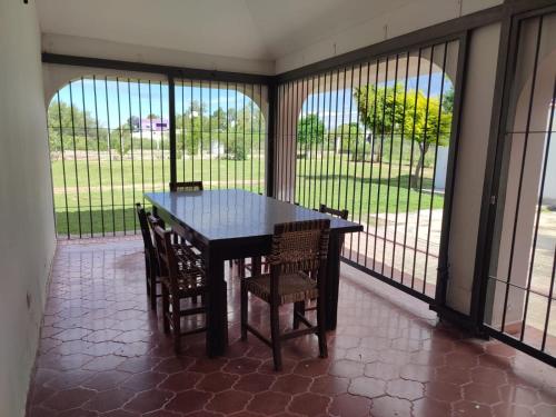 une table et des chaises dans une pièce avec fenêtres dans l'établissement Chalet Del Lago, à Termas de Río Hondo