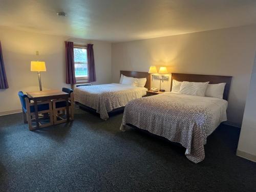 a hotel room with two beds and a table at Bay Motel in Green Bay