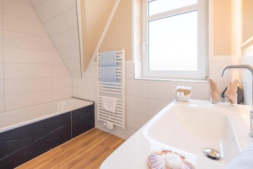 a white bathroom with a tub and a sink at Seeblick Genuss und Spa Resort Amrum in Norddorf