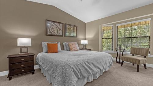 a bedroom with a bed and a chair and two windows at Luxury Townhome - 5 minutes to Disney in Orlando