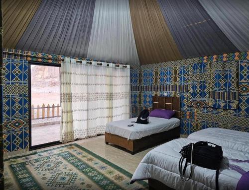 a room with two beds and a window in a tent at Remal Wadi Rum Camp & Tour in Disah