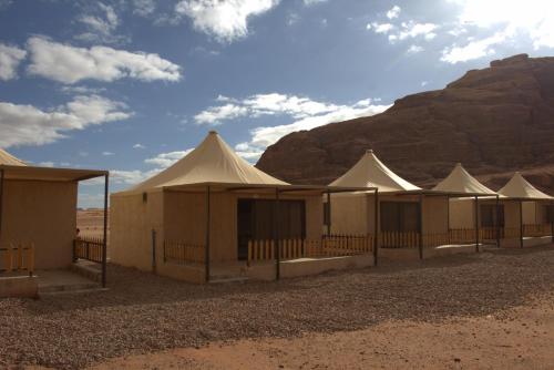 rząd namiotów z górą w tle w obiekcie Remal Wadi Rum Camp & Tour w mieście Disah