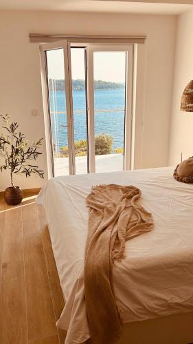 a bedroom with a bed with a view of the ocean at BohoSol House in Blato