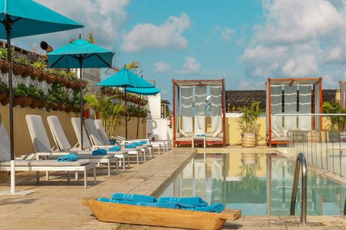 a pool with lounge chairs and umbrellas at a hotel at Nacar Hotel Cartagena, Curio Collection by Hilton in Cartagena de Indias