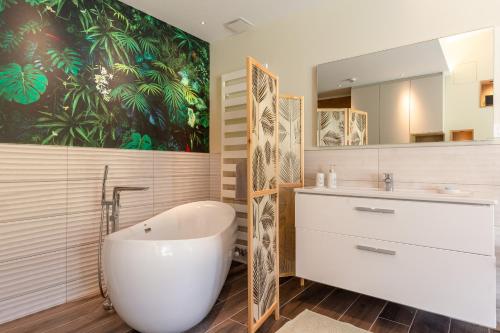 a bathroom with a tub and a sink and a mirror at Eden'Roc in Labaroche