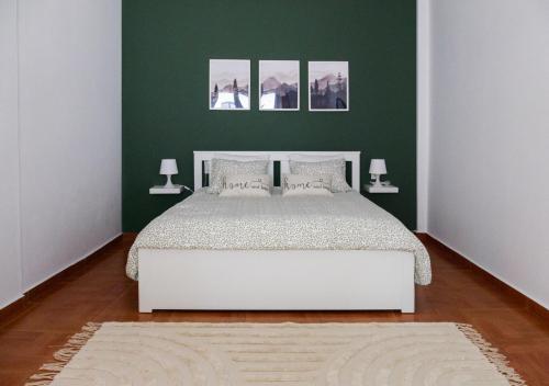 KtistádesにあるARBOR Ktistades hostingの緑の壁に白いベッドが備わるベッドルーム1室