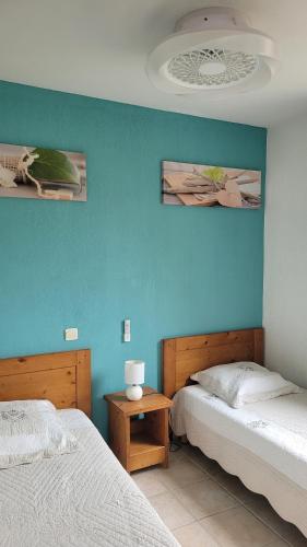 une chambre avec deux lits et un mur bleu dans l'établissement Le Hameau du Moulin, à Montignac