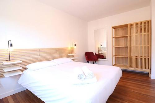 a white bedroom with a large bed and a red chair at Notel Club - Oasis urbano en Santander in Santander