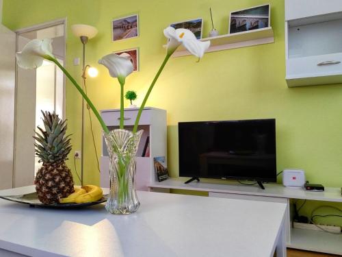 een vaas met bloemen en een ananas op een tafel bij Apartman Lola in Višegrad
