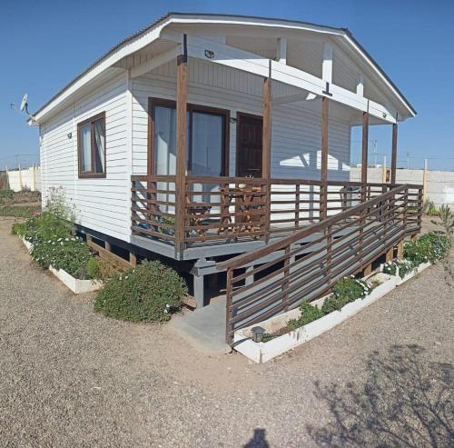 a white house with a porch on the beach at Atardeceres Tongoy - Cabaña 4 personas condominio privado Tanguemar in Coquimbo