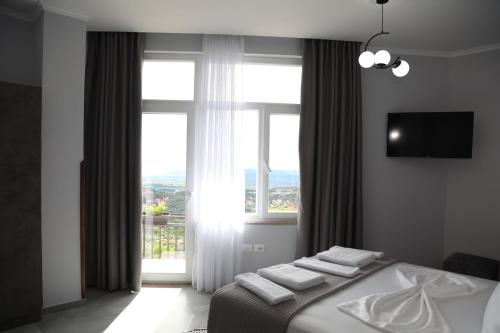 a bedroom with a bed and a large window at DEAL Castle View Rooms in Krujë
