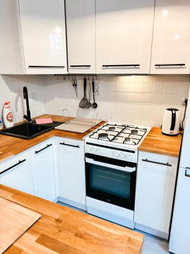 a kitchen with white cabinets and a stove top oven at Apartament Curie in Tychy