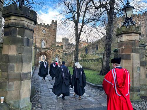 un grupo de personas con batas de graduación entrando en un castillo en Saint Leonard’s Durham City en Durham