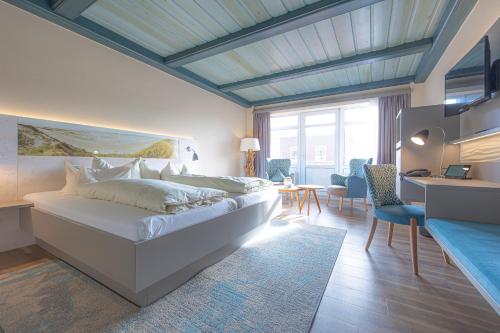 a bedroom with a large white bed and a desk at Seeblick Genuss und Spa Resort Amrum in Norddorf
