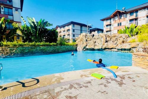 a child playing in a pool at a resort at Casa con Amor - 2 BR Pastel Boho-Chic Haven in Manila