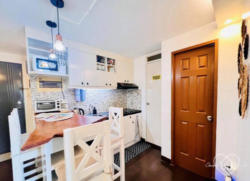a kitchen with white cabinets and a wooden table at Casa con Amor - 2 BR Pastel Boho-Chic Haven in Manila
