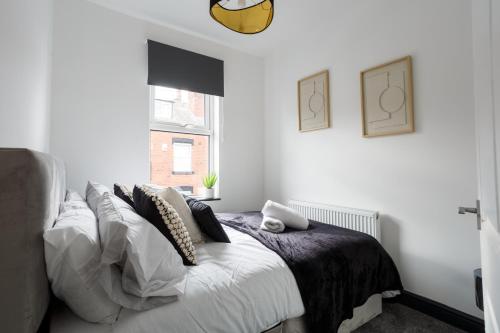 um quarto branco com uma cama com almofadas e uma janela em Spacious Three-Bedroom Apartment in Leeds em Leeds