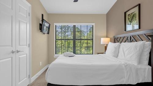 a bedroom with a large white bed and a window at Deluxe Townhome - 5 min to Disney World in Orlando