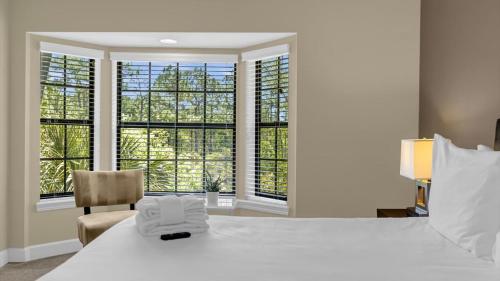 a bedroom with a bed and a chair and windows at Sunny Summer in Orlando - TownHome by Disney! in Orlando