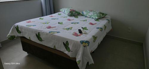 - un lit avec une couette et des oreillers blancs dans l'établissement Casa Temporada Sereia do Mar, à São Mateus